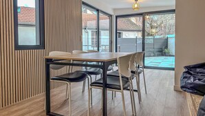 Ett modernt matområde med ett träbord och stolar, stora fönster och utsikt över trädgården.