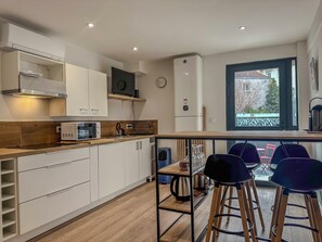 Una cocina moderna con armarios blancos, microondas, cafetera y ventana con vistas al exterior.