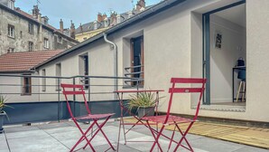 A terrace with red folding chairs and a table, a potted plant, and a view of neighboring buildings. - #IM | The Victoria 10 💟 (Grenoble)