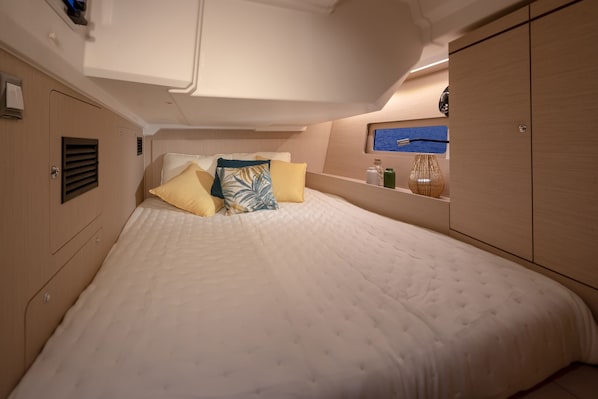 Ein Schlafzimmer mit einem Bett, Kissen, einem Regal mit Gegenständen und Meerblick.