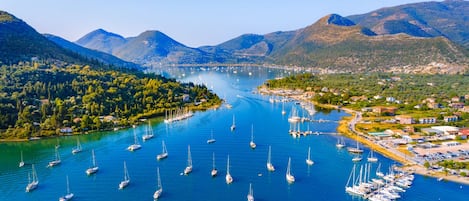 A marina with numerous sailboats docked, surrounded by lush green hills and mountains.