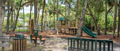 A playground with a slide, swings, and a small wooden structure.