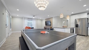 Une cuisine moderne équipée d’une table de ping-pong, d’appareils électroménagers en acier inoxydable et d’une grande fenêtre.