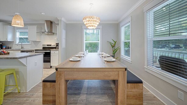 Une cuisine moderne dotée d’un îlot central, de luminaires suspendus et offrant une vue sur l’extérieur grâce à de grandes fenêtres.