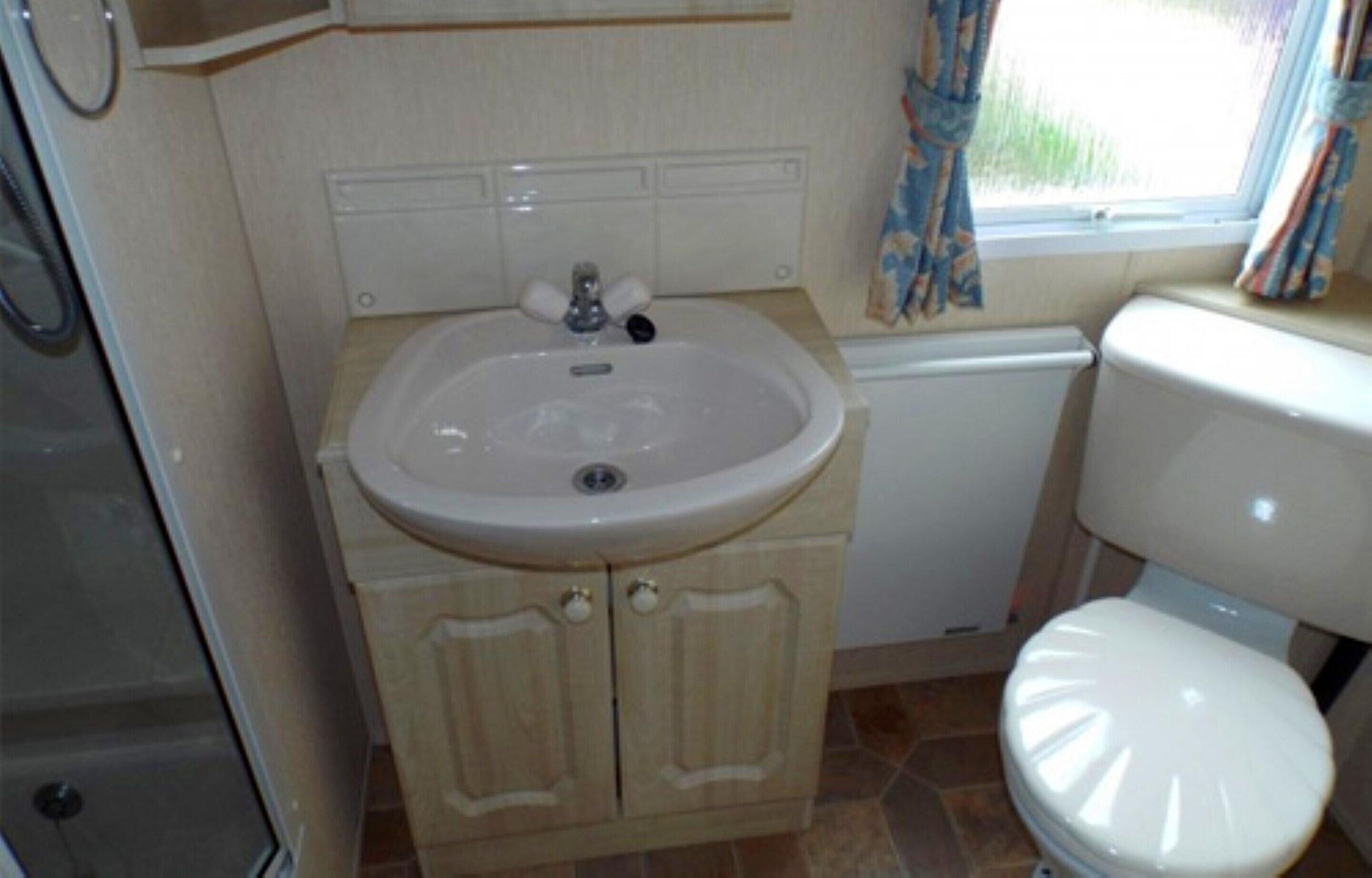 A compact bathroom with a sink, toilet, and cabinet.