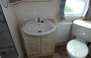 Ein kleines Badezimmer mit Waschbecken, Toilette und Schrank.