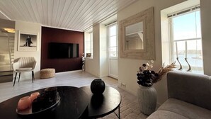 Een moderne woonkamer met een flatscreen televisie, een bank, een salontafel en een groot raam.
