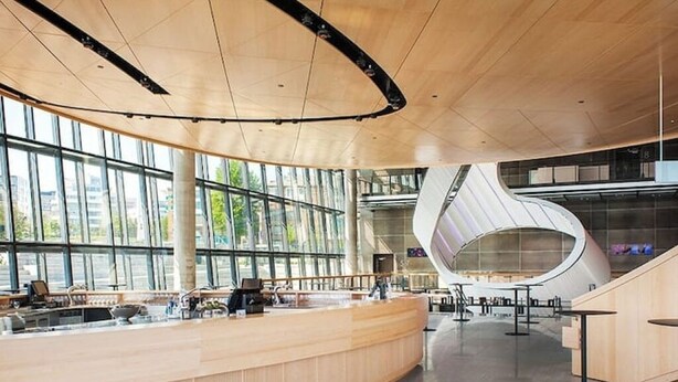 Een modern interieur met een gebogen receptiebalie, grote ramen en een opvallende spiraaltrap.