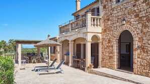 A stone building with a balcony, outdoor seating, and lounge chairs. - Finca with private pool in a quiet location near Felanitx (Felanitx)