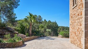 A stone pathway leading to a building with a stone facade, surrounded by greenery and trees. - Finca with private pool in a quiet location near Felanitx (Felanitx)