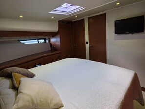 Une chambre à coucher avec un lit, des oreillers, une lucarne, une armoire et un téléviseur à écran plat.