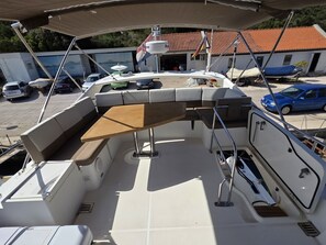 Un pont de bateau équipé de sièges, d’une table et d’un espace abrité.