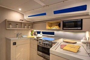 Eine kompakte Küche mit Herd, Backofen, Mikrowelle und Spüle.