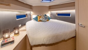 A modern bedroom with a large bed, bedside lamps, and a small window. - Caribbean Dream: Sun-soaked Sailing Adventure from Tortola, Islas Vírgenes Británicas (Road Town)
