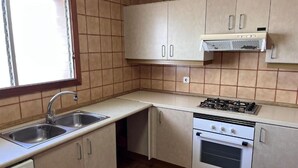 A compact kitchen with a gas stove, a built-in oven, a sink, and light-colored cabinets. - Spacious 3-bedroom apartment on the front line by the sea. Rodes Lux-71 (Calafell)