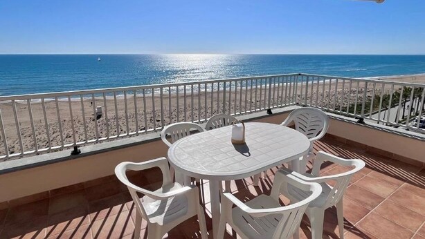 A balcony with a table and chairs overlooking a beach. - Spacious 3-bedroom apartment on the front line by the sea. Rodes Lux-71 (Calafell)