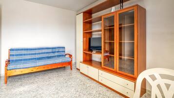 Een kamer met een houten bank, een kast met glazen deuren en een witte stoel.