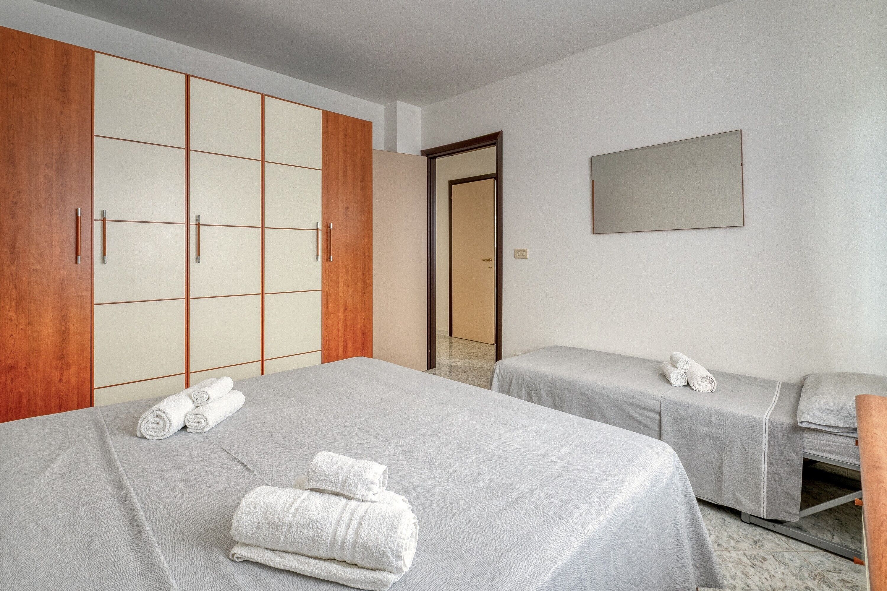Habitació d'hotel amb dos llits, un armari i un mirall.