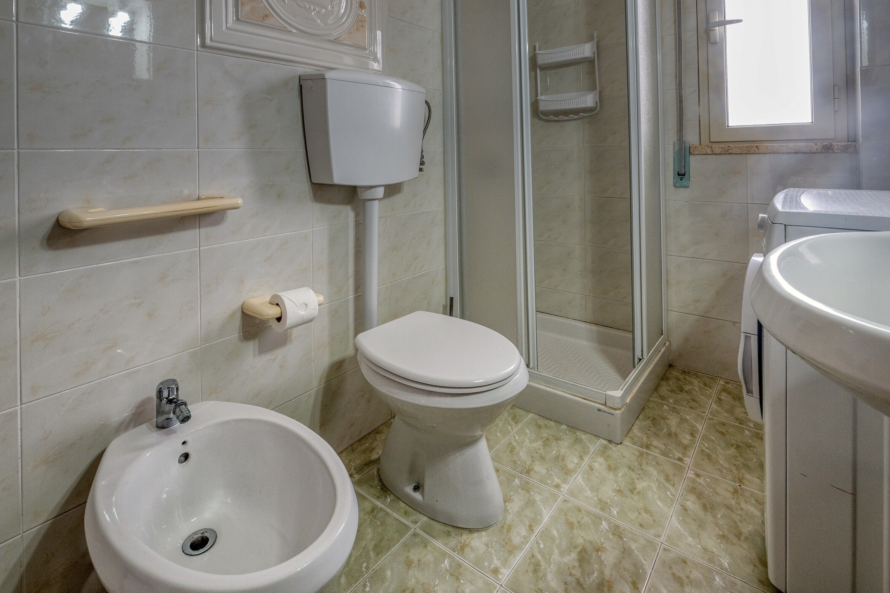 A bathroom with a toilet, bidet, sink, and shower.