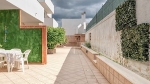 A courtyard with a tiled floor, a table with chairs, a green wall, and a brick wall with ivy. - Residence do Mestru Luccio Apt. Tripoli (San Pietro In Bevagna)