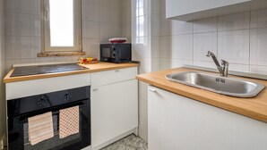 A compact kitchen with a built-in oven, a microwave, a sink, and a window providing natural light. - Residence do Mestru Luccio Apt. Tripoli (San Pietro In Bevagna)