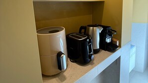 Ett litet kök med en kaffebryggare, brödrost och vattenkokare på bänkskivan.