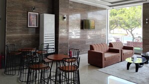A modern interior with a sofa, coffee table, and dining area with chairs. - Nilufer AlHada Hotel (Taif)