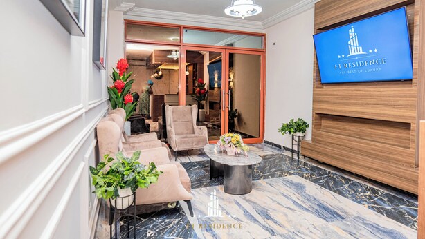 A lobby with a reception desk, plush seating, and a large TV screen displaying "FT Residence". - FT Residence (Douala)