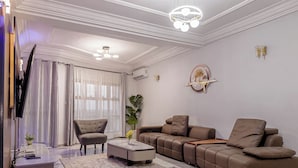 A modern living room with a sofa, armchairs, a coffee table, and a TV. - FT Residence (Douala)