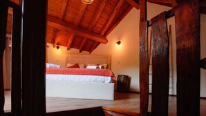 A bedroom with a wooden ceiling, a bed with white bedding and red accents, and a nightstand. - O Palheiro by CVL (Melgaço)