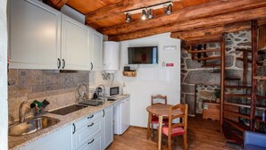 A compact kitchen with white cabinets, a granite countertop, and a wooden dining table with chairs. - O Palheiro by CVL (Melgaço)