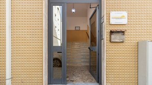 Entrada de hotel con pared texturizada, una puerta, una escalera y un letrero que dice 'SUMMERTIME HOUSE'.