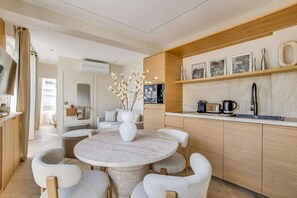 A modern kitchen with a round dining table, white chairs, and a vase of flowers. - A Wonderfull 1-Br - Opéra (Paris)