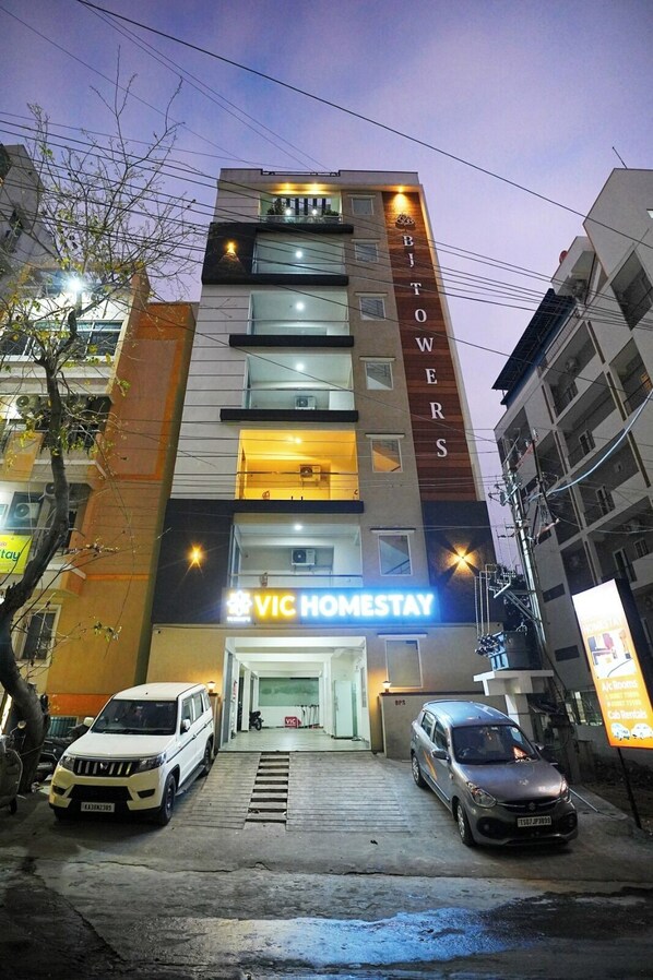 Un immeuble à plusieurs étages, orné d’une enseigne « VIC HOMESTAY », doté de balcons et présentant un design architectural moderne.