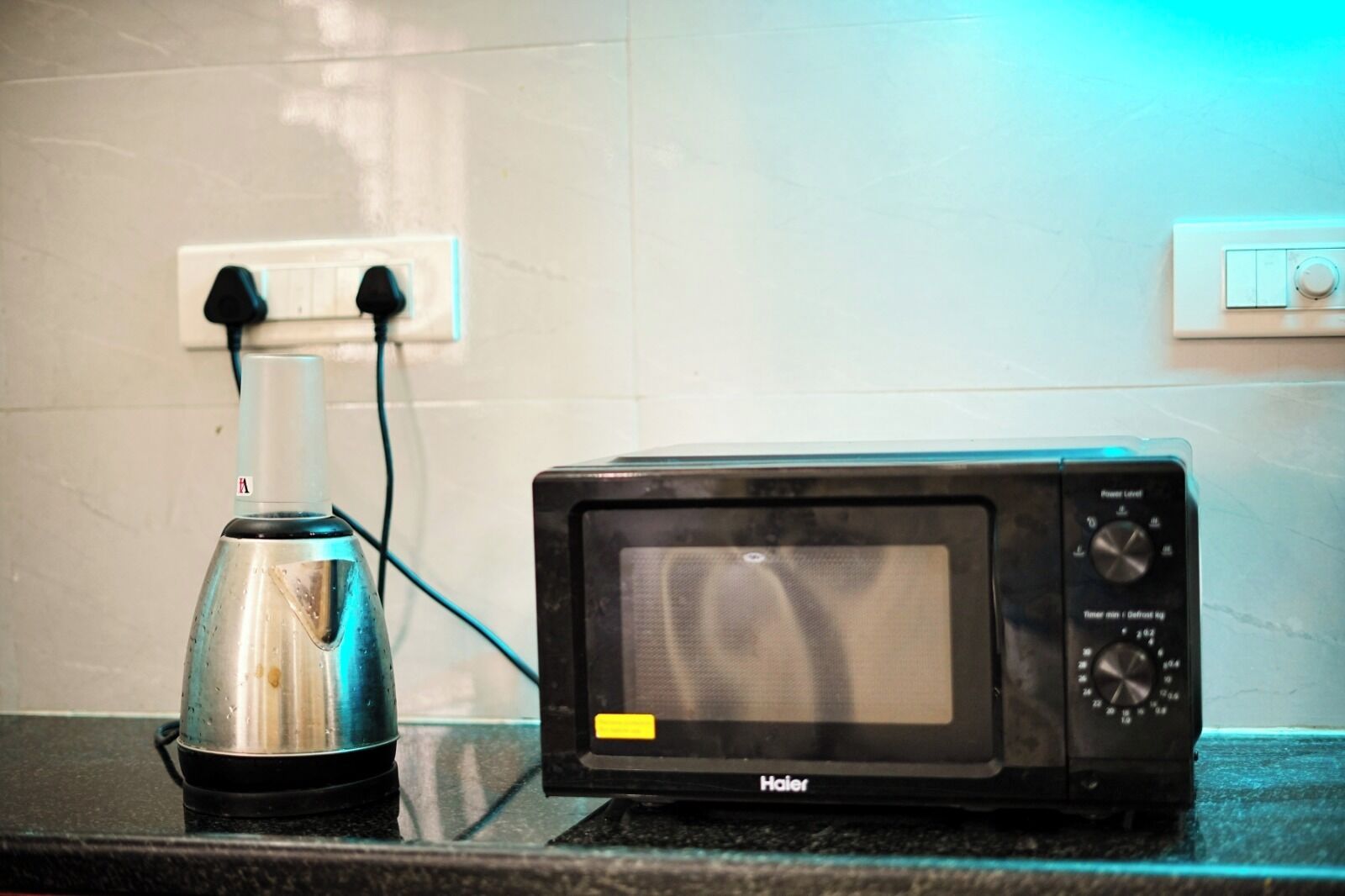A kitchen with a microwave and a kettle on the counter.