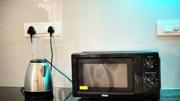 A kitchen with a microwave and a kettle on the counter.