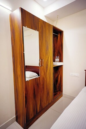 Une armoire en bois avec un miroir, un lit et une étagère avec des bouteilles.