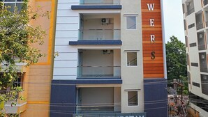 En bygning med flere etager, hvor der står "BLOWERS" på facaden, med altaner og et skilt med "VIC HOMESTAY" ved indgangen.