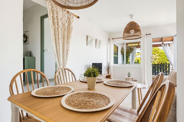 A dining area with a wooden table, woven placemats, and a potted plant.