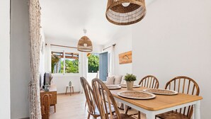 A dining area with a wooden table, chairs, and hanging wicker light fixtures.