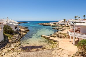 A coastal town with clear blue waters, rocky shoreline, and white buildings with balconies. - Apartamento Tramuntana Biniancolla by Escape Home (Biniancolla)