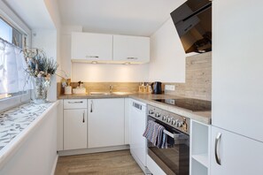 Una cocina moderna con armarios blancos, encimera de madera y horno empotrado.