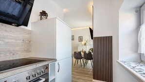 Una cocina compacta con estufa integrada, un refrigerador y un comedor con sillas y una mesa.