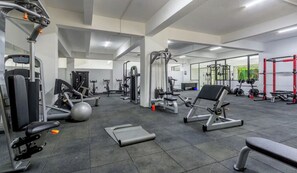 Une salle de sport moderne équipée de divers appareils d’exercice, notamment des machines de musculation, un tapis de course et un rameur.