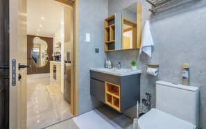 Une salle de bain moderne équipée d’un lavabo, d’un miroir, de toilettes et d’un espace douche.