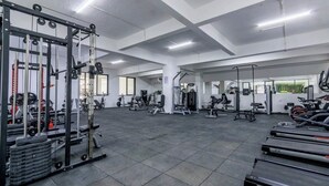 Una àmplia sala de gimnàstica amb diversos equips d'exercici, incloent cintes de córrer, aparells de peses i peses lliures.