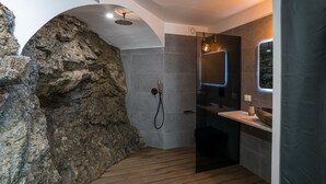 A modern bathroom with a stone wall, a shower, a sink, and a mirror. - Sant' Anna Deluxe (Menaggio)