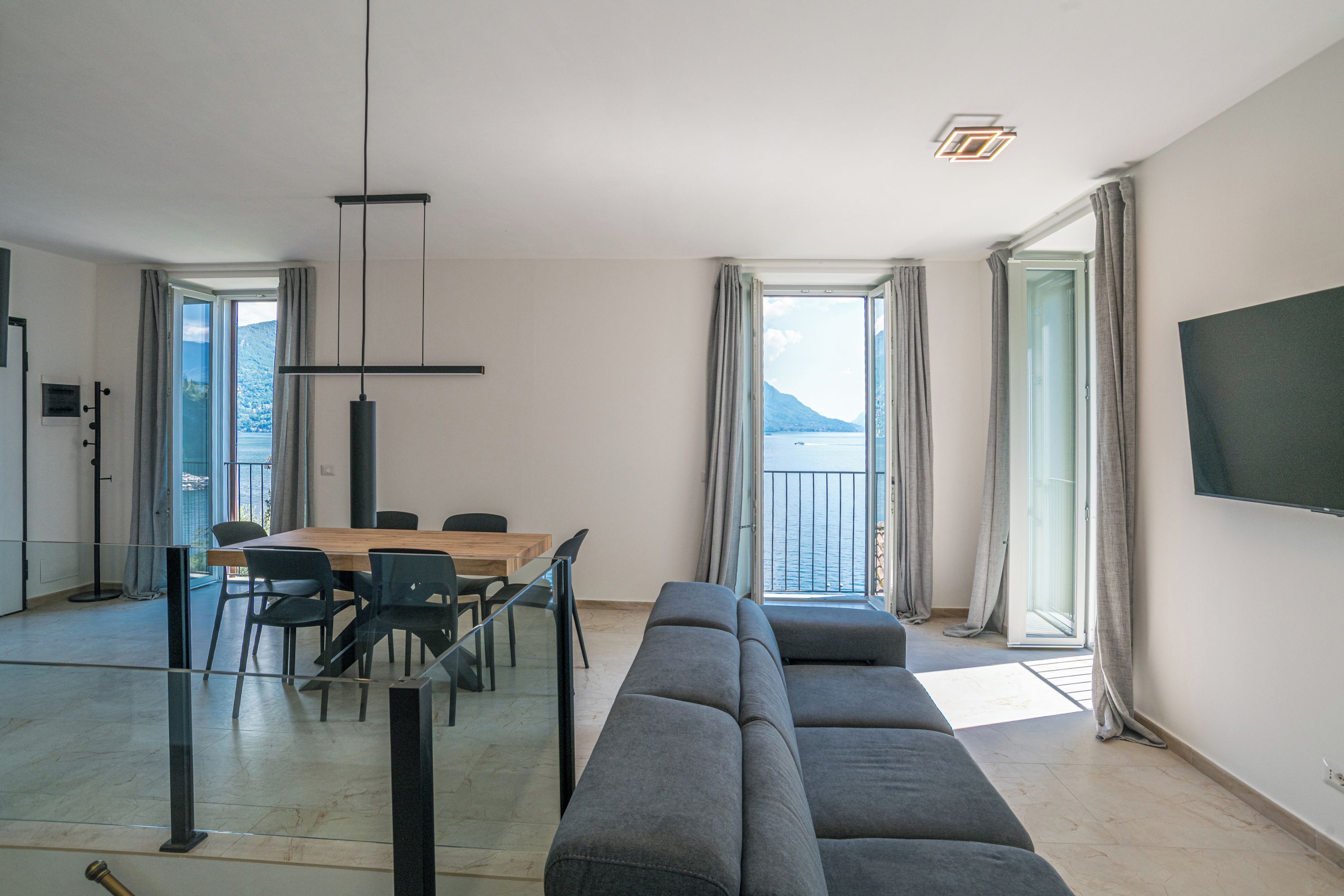 Ein modernes Wohnzimmer mit einer Couch, einem Esstisch, Stühlen und einem Fernseher.