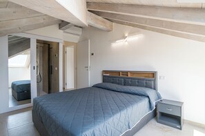A bedroom with a bed, a nightstand, and a door leading to another room. - Sant' Anna Deluxe (Menaggio)