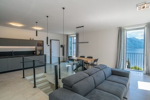 A modern living area with a sofa, dining table, and kitchen. - Sant' Anna Deluxe (Menaggio)
